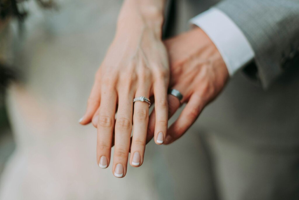 Husband and wife gently holding hands, wedding rings visible
