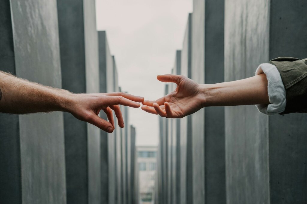 Two hands reaching toward each other across a gap, symbolizing reconciliation